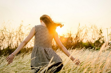 Lady in a field with sun in the background