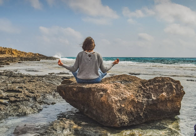 Woman coping with panic attacks by meditating on the beach