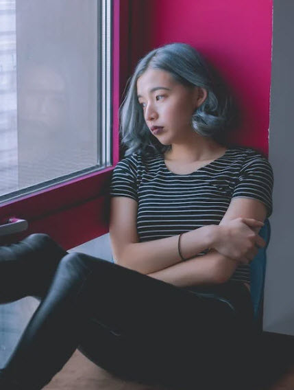 Woman sitting by window suffering from self-esteem issues